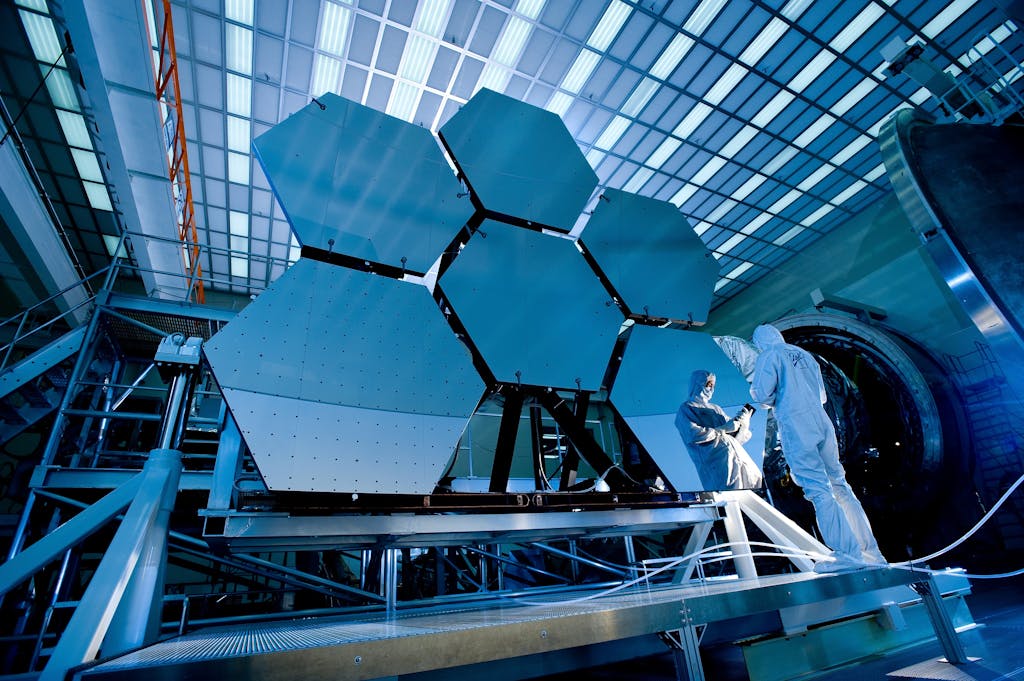 Ezra wave innovation Engineers in protective suits work on telescopic mirrors in a high-tech lab.